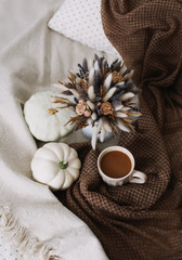 Obraz na płótnie Canvas Coffee cup with flowers and pumpkins on a cozy plaid. Autumn still life. Breakfast in bed. Good morning. Stylish autumn flat lay. 