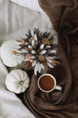 Coffee cup with flowers and pumpkins on a cozy plaid. Autumn still life. Breakfast in bed. Good morning. Stylish autumn flat lay. 