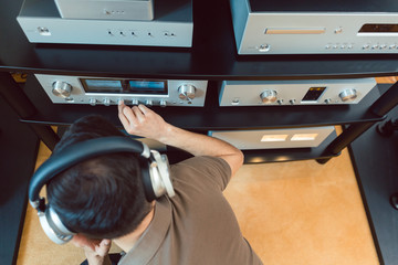 Man turning up the volume on home Hi-Fi stereo