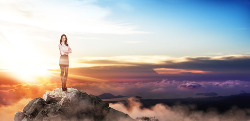 Young buiness woman stands on the top of the mountain.