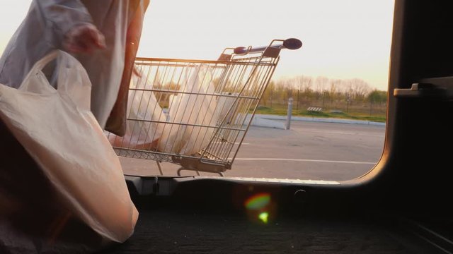 Woman puts shopping bags in the trunk of a car. View from inside the car