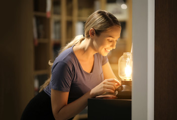 Women lighting up on lamp light in dark room