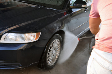 Summer car wash on a contactless self-service car wash. Cleaning a car using high pressure water.
