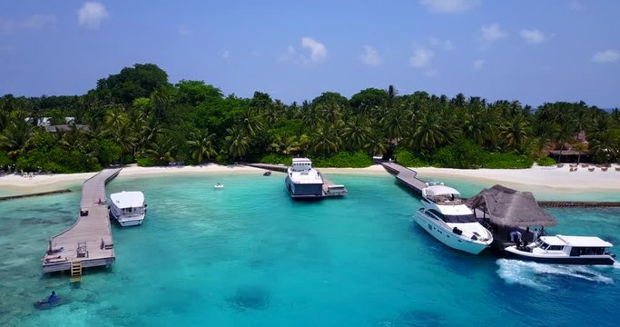 Aerial side movement drone shot of an exotic pier in the Maldives with some boats on it 4K