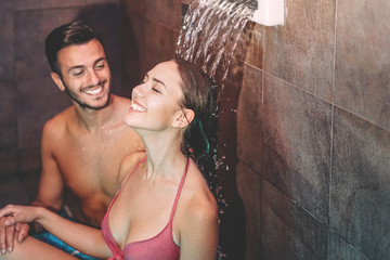 Happy couple having fun in luxury spa resort hotel - Romantic young people doing relaxing wellness waterfall treatment together - Love relationship and healthy well being lifestyle concept