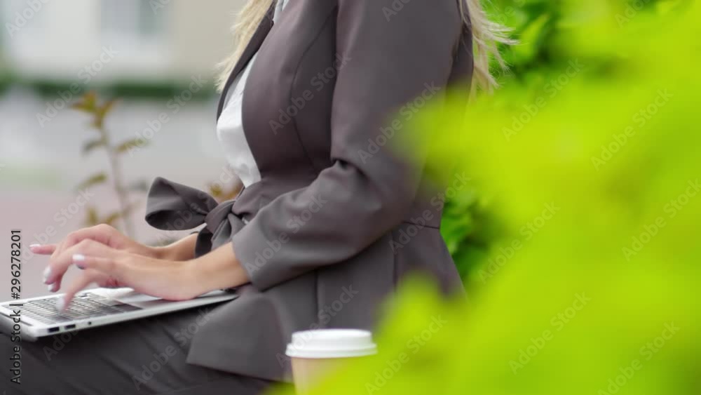 Poster tracking medium shot of unrecognizable businesswoman using laptop computer while having coffee on be