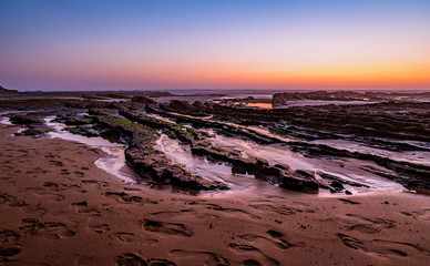 Rock formations emerge with low tide at Monte Clerigo, Algarve (Portugal)