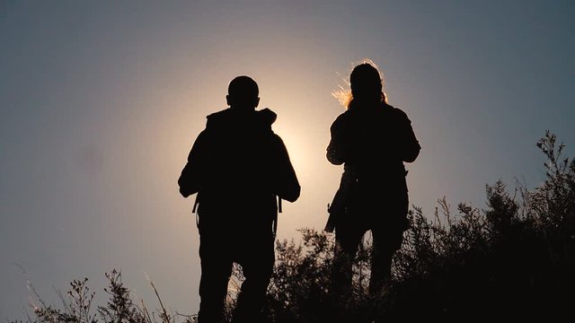 teamwork tourists travel concept slow motion video. hiking silhouette happy family couple man and girl go hiking climbing a mountain. lifestyle walking on nature. tourists with backpacks traveling