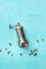 Allspice, Jamaican pepper. Black peppercorns with a vintage pepper mill, top shot on a blue...