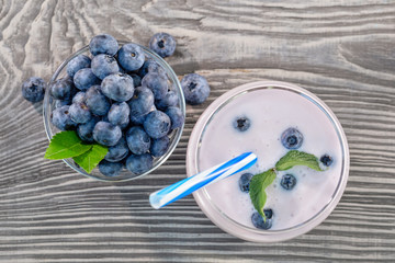 Berry smoothie or yogurt in glass and blueberries in bowl on wooden table