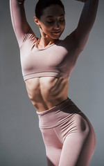 You can see the ribs. Caucasian pretty woman stands against wall in the studio at daytime