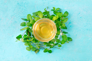Mint tea cup, overhead shot on a blue background with vibrant fresh leaves