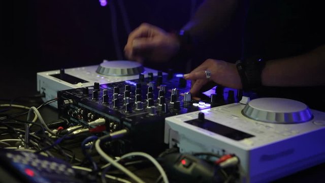 DJ work in a nightclub. DJ stands behind the mixing console.