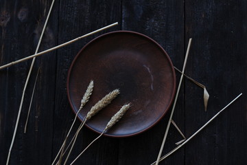 three wheat spikelets on a clay plate on a black burnt