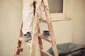Worker standing on wooden ladder.