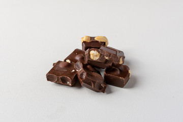 Dark chocolate on white background with whole hazelnuts