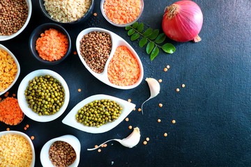 Composition of dry legumes. Assortment of colorful legumes in bowls. Lentils, Moth beans, Mung Beans, Masoor or red lentils, Split Chickpea, Toor Dal, Raw Split Mung Bean Lentils, Yellow Split.