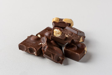 Dark chocolate on white background with whole hazelnuts