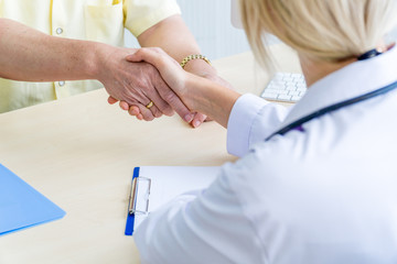 Female doctor shaking hand with the elderly male patient.