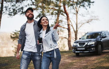 Obraz premium Beauty of the nature. Couple have arrived to the forest on their brand new black car