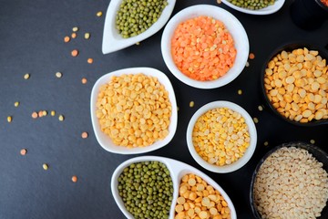 Composition of dry legumes. Assortment of colorful legumes in bowls. Lentils, Moth beans, Mung Beans, Masoor or red lentils, Split Chickpea, Toor Dal, Raw Split Mung Bean Lentils, Yellow Split.