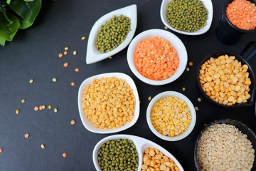 Composition of dry legumes. Assortment of colorful legumes in bowls. Lentils, Moth beans, Mung Beans, Masoor or red lentils, Split Chickpea, Toor Dal, Raw Split Mung Bean Lentils, Yellow Split.
