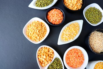 Composition of dry legumes. Assortment of colorful legumes in bowls. Lentils, Moth beans, Mung Beans, Masoor or red lentils, Split Chickpea, Toor Dal, Raw Split Mung Bean Lentils, Yellow Split.
