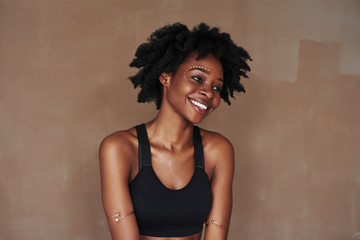 Young beautiful afro american woman in the studio against brown background