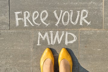 Free your mind text on gray sidewalk with woman legs, top view