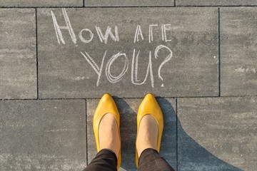 How are you written on gray sidewalk with women legs, top view