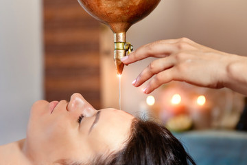 ayurveda massage alternative healing therapy.beautiful caucasian female getting shirodhara...