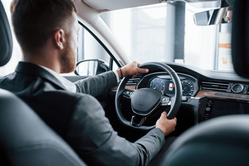 Modern businessman trying his new car in the automobile salon