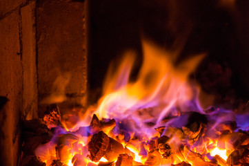 Bright fire burns on coals close-up. Carbon dioxide flies out with a blue spark.