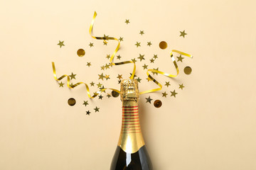 Champagne bottle and glitter on beige background, space for text
