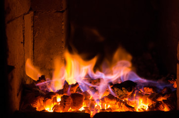 Bright fire burns on coals close-up. Carbon dioxide flies out with a blue spark.