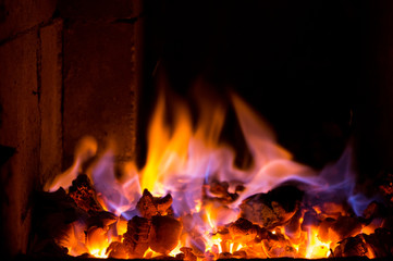 Bright fire burns on coals close-up. Carbon dioxide flies out with a blue spark.