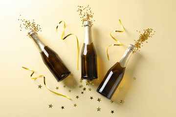 Champagne bottles and glitter on beige background. Holiday concept