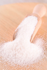 White cane sugar on a light wooden background