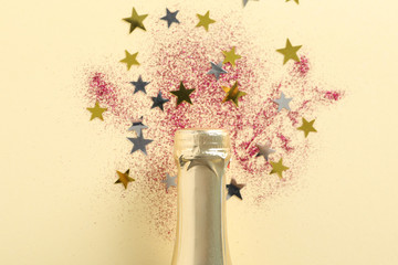 Champagne bottle and glitter on beige background, close up