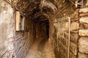 Old abandoned tunnel in the slum underground cellar. Entrance to urban catacombs. Underside of city overpass concrete old worn repair dirty industrial construction infrastructure arch beam