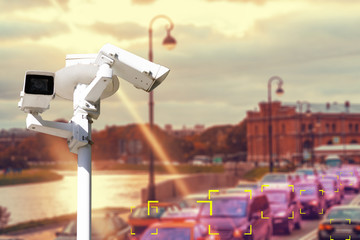 The concept of video surveillance and security technology. CCTV camera on the background of a road bridge with traffic in cloudy weather with a Sunny sunset. Color definition zone