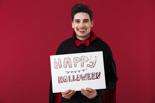 Image of vampire man in black costume holding halloween paper board