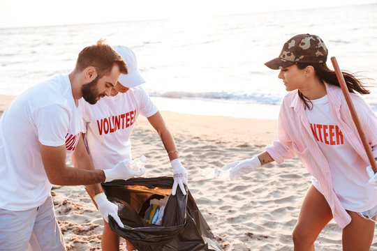 Image of altruistic volunteers cleaning beach from plastic with trash bags
