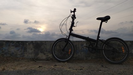 Fototapeta na wymiar Bicycle on beach at sunset with sky background