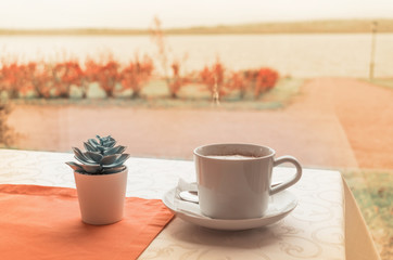A cup of morning cappuccino near a lake. Enjoy coffee time.