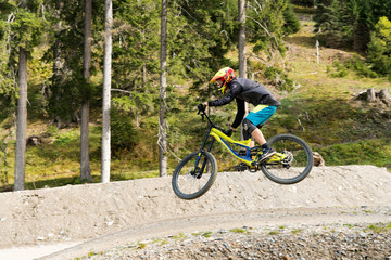 downhill mountain biker jumping high and riding hard in Lenzerheide in the Swiss Alps