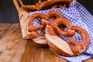 Bavarian pretzel decorated with a blue and white cloth on a rustic wooden board - Munich Oktoberfest. Background and free space for text. Traditional pastries for the festival.