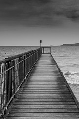 Moody black and white seascape and a jetty.