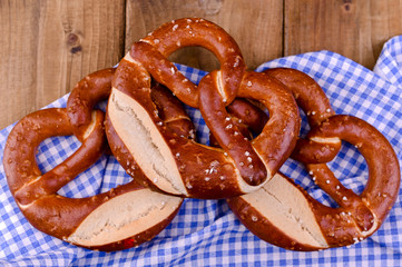 Bavarian pretzel decorated with a blue and white cloth on a rustic wooden board - Munich Oktoberfest. Background and free space for text. Traditional pastries for the festival. Close-up.