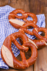 Bavarian pretzel decorated with a blue and white cloth on a rustic wooden board - Munich Oktoberfest. Vertical format. Background and free space for text. Traditional pastries for the festival.